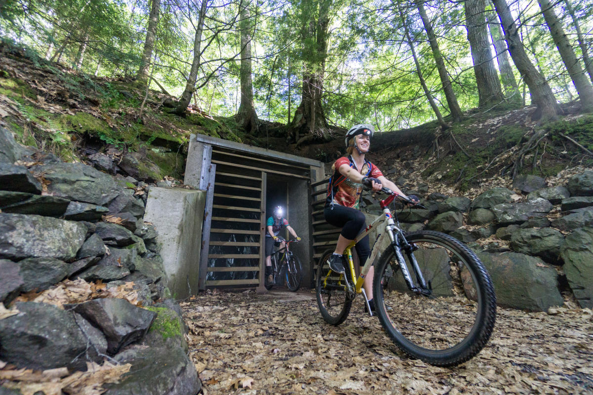 Two bikers ride through mine opening.