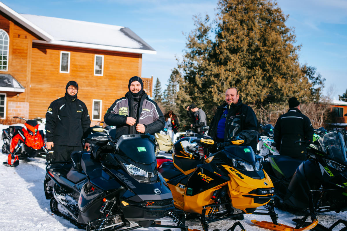 a group of people on their snowmobiles smile for a photo