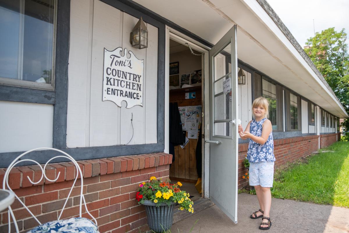 a child holds open the door of a local diner