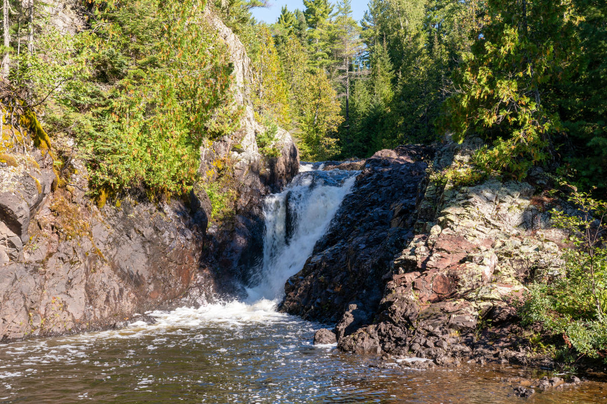 Photo of Upper Montreal Falls surrounded in vibrant green leaves.