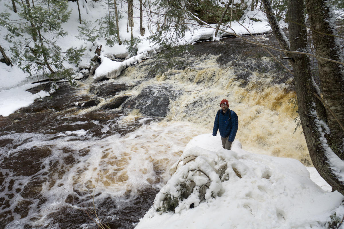 Man hikes around winter waterfall.