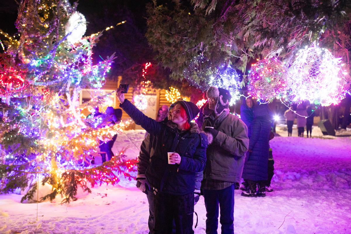 a person marvels at a snowy park covered in holiday lights
