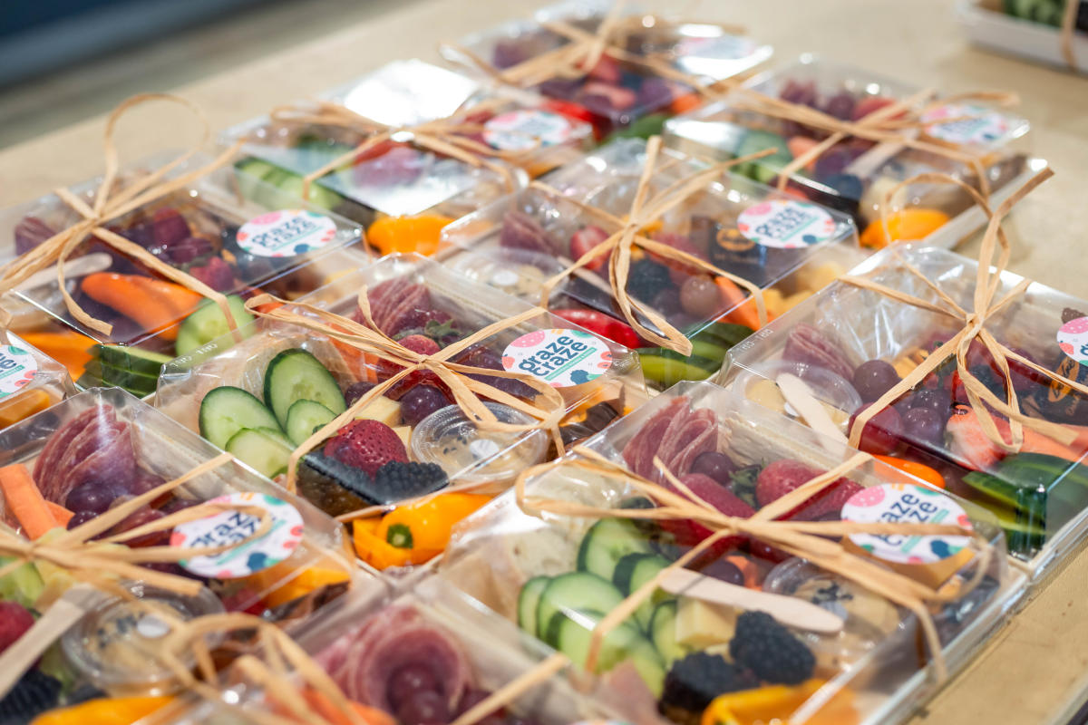 A table piled with grab 'n go charcuterie boxes from Graze Craze.