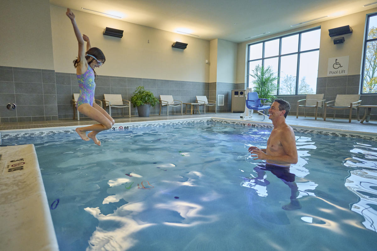 Girl jumping into the pool with dad