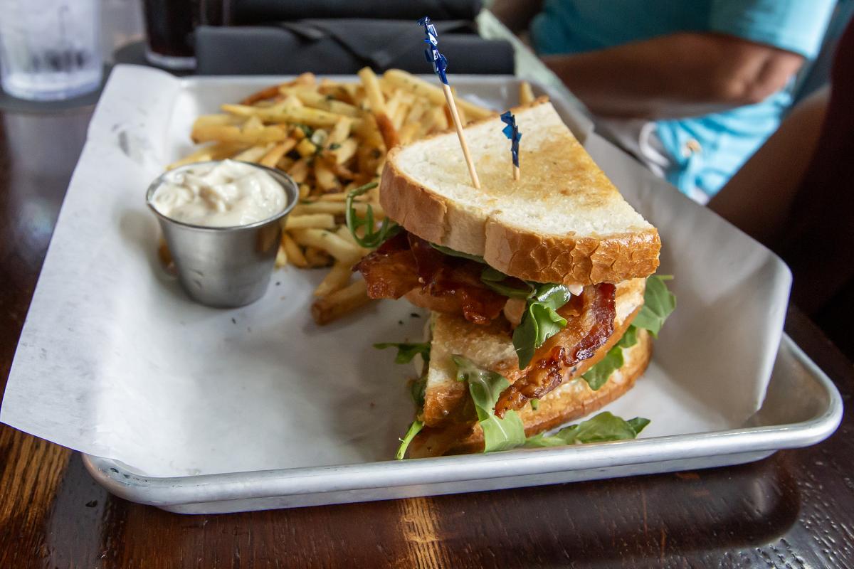 BLT sandwich with fries and a dipping sauce on a metal serving tray