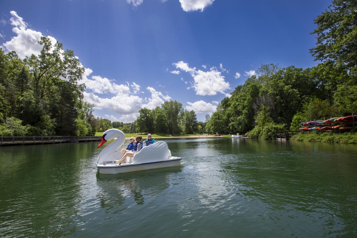 People in the swan pedal boats at the pond at Burchfield Park