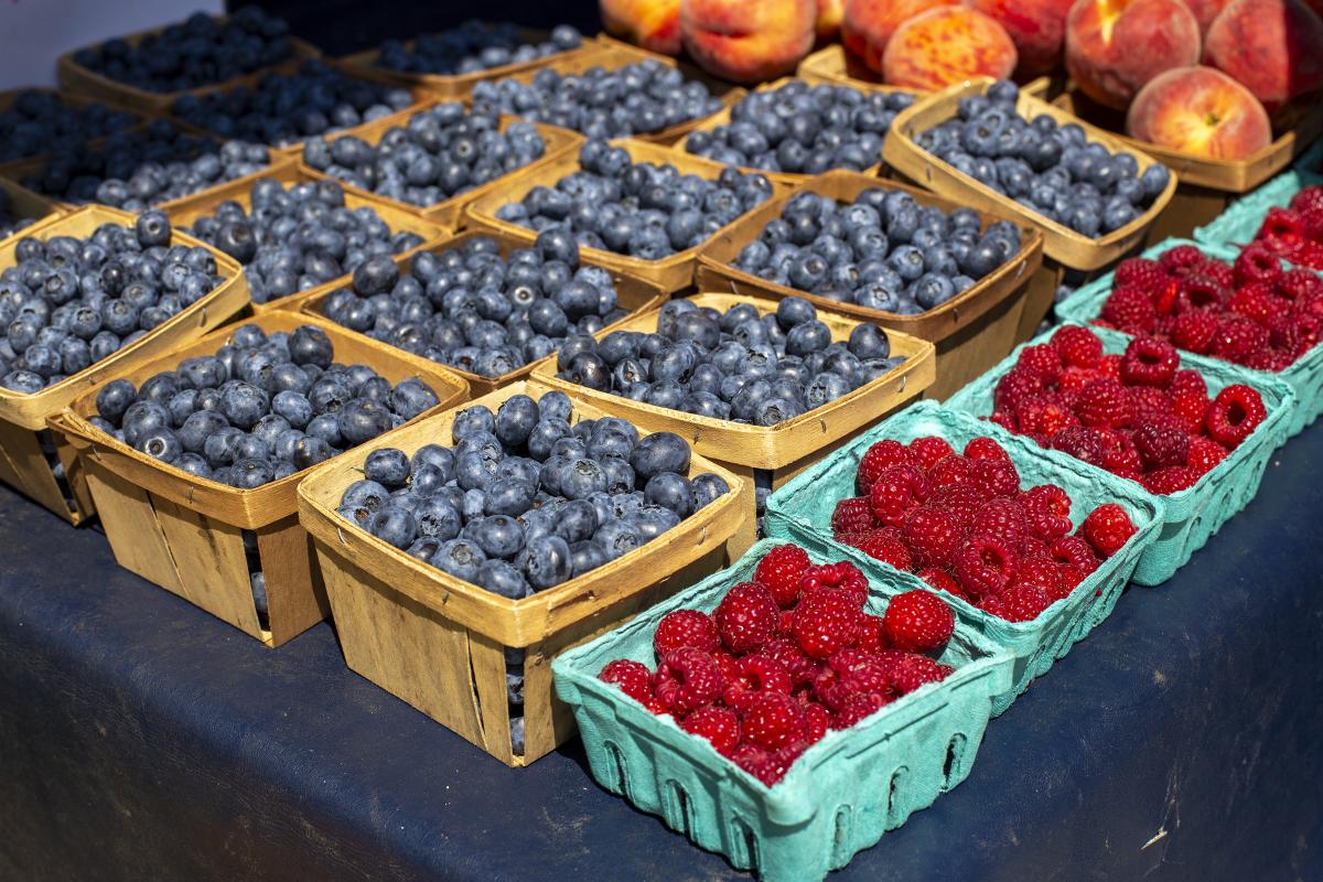 Containers of blueberries and raspberries on a table at a farmers' market