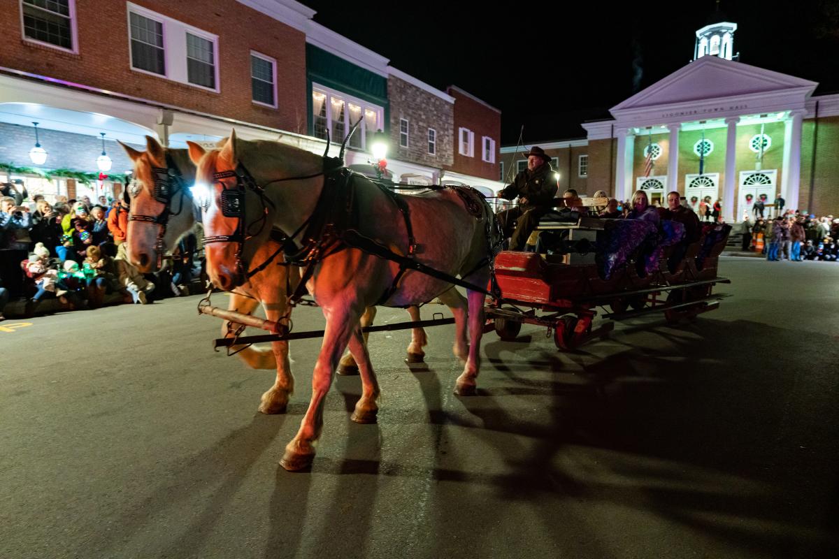 A horse-drawn carriage carries visitors past Ligonier Town Hall during Light-Up Ligonier.