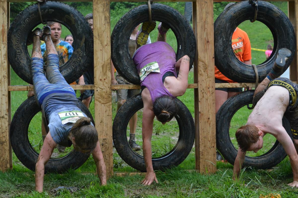 Kids’ Mud on the Mountain participants dive through tires during the competition