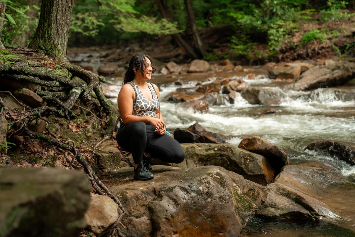 hiking woman bending by a stream at Linn Run