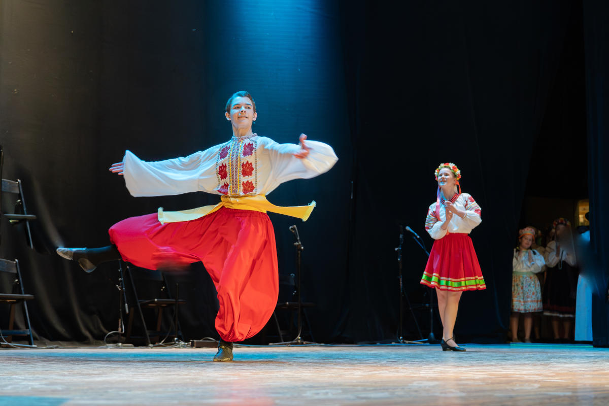 Photo showing two Mavka Dancers in colorful traditional attire, dancing onstage at the KU Center for Russian, East European, and Eurasian Studies' Annual Spring Festival at Liberty Hall in Lawrence, Kansas.