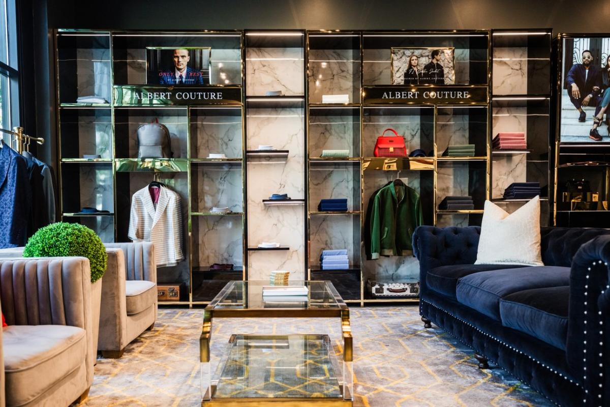 Men's clothing store with sport coats and shirts hanging on the wall, includes a sitting area with couches and coffee table