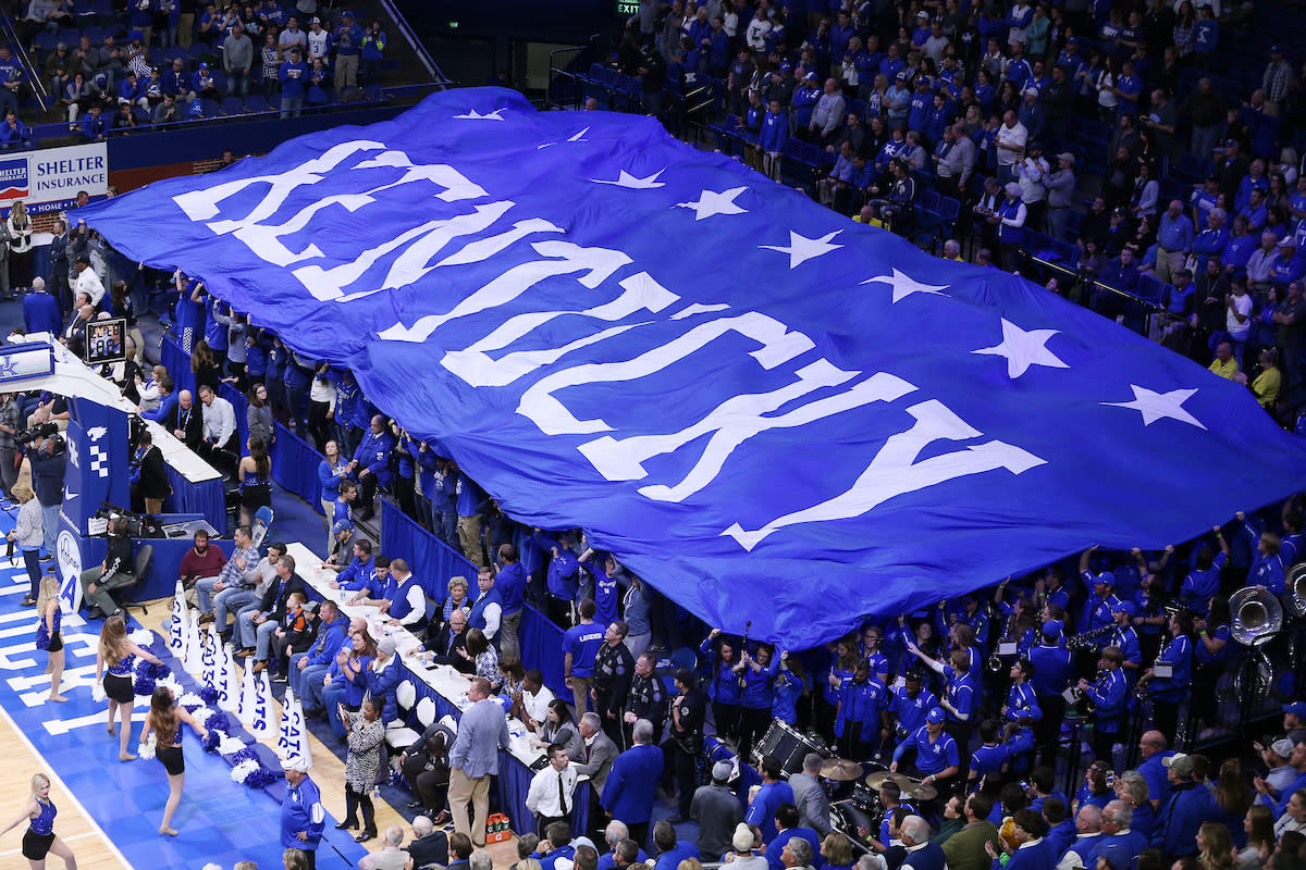 People at a Kentucky Basketball game celebrating with a huge banner saying Kentucky.