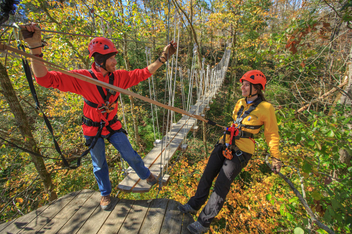 Two people on zipline at Boone Creek Outdoors in the fall.