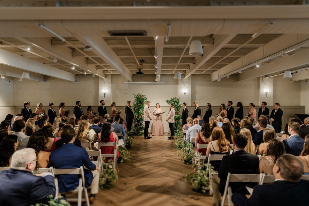 Groom and groom at wedding alter in room full of people