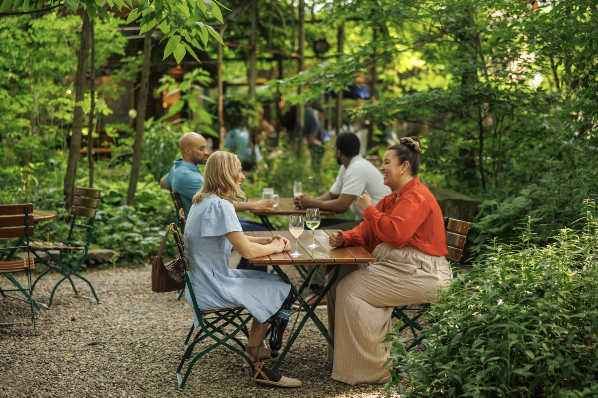 Two individuals drinking wine at a garden cafe