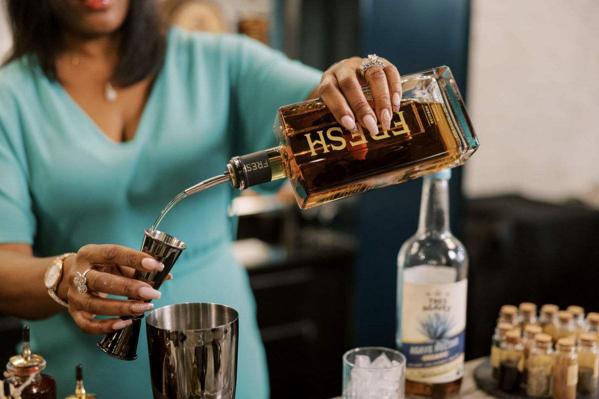 Person pouring bourbon into a measuring shot glass