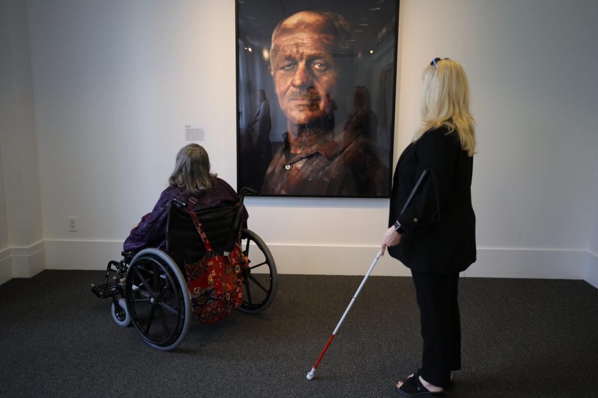 Two women look at art on the wall