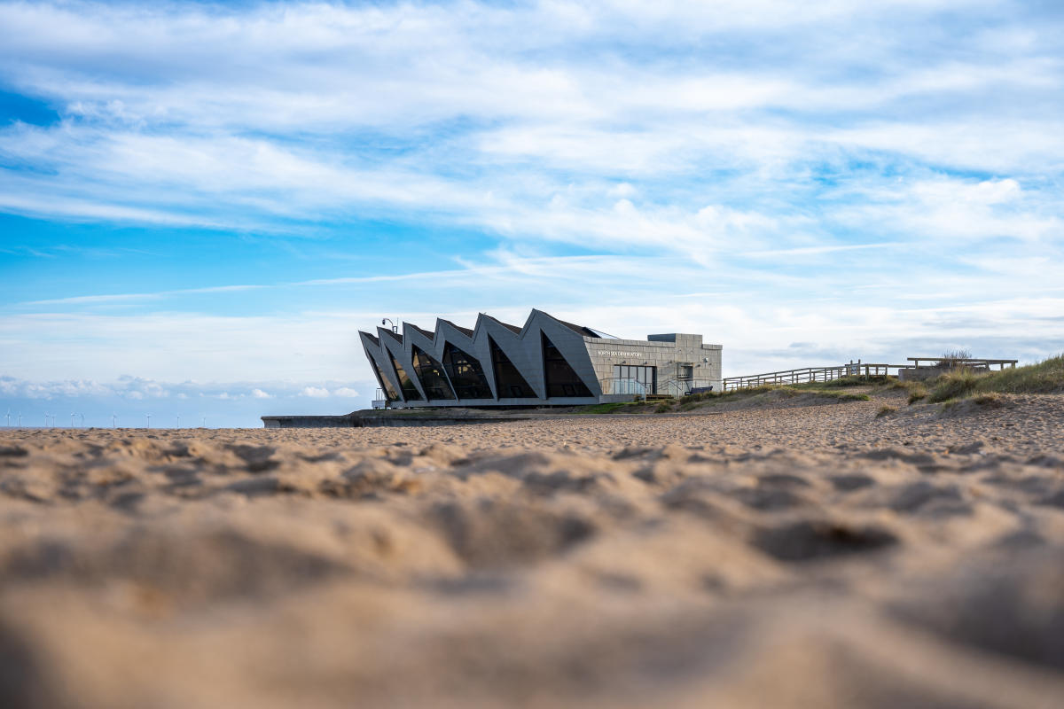 A far away view of North Sea Observatory surrounded by a sandy beach