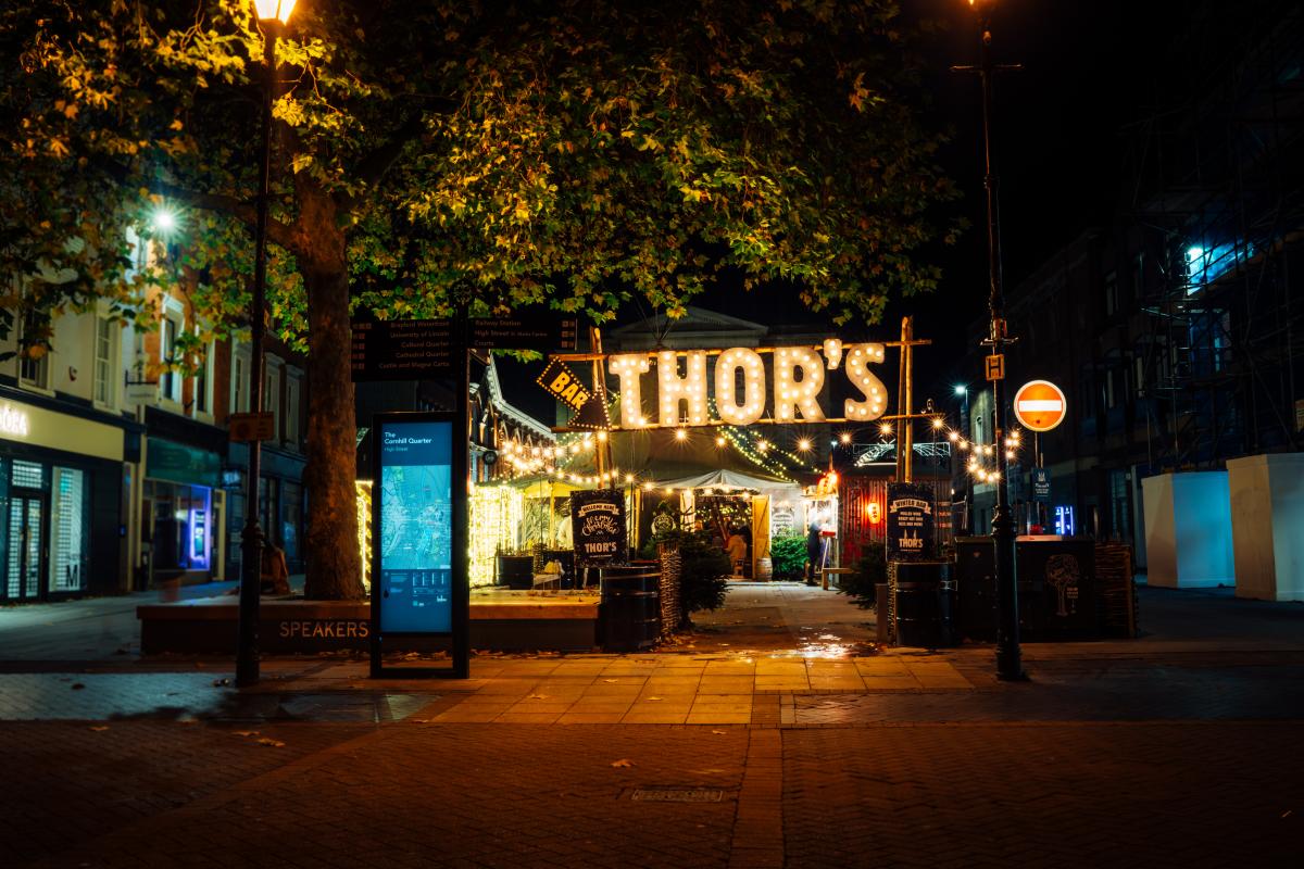 Image shows Thors Tipi Bar - a Christmas pop-up bar in the centre of Lincoln. A neon sign glows with the name 'Thors' in spotlights