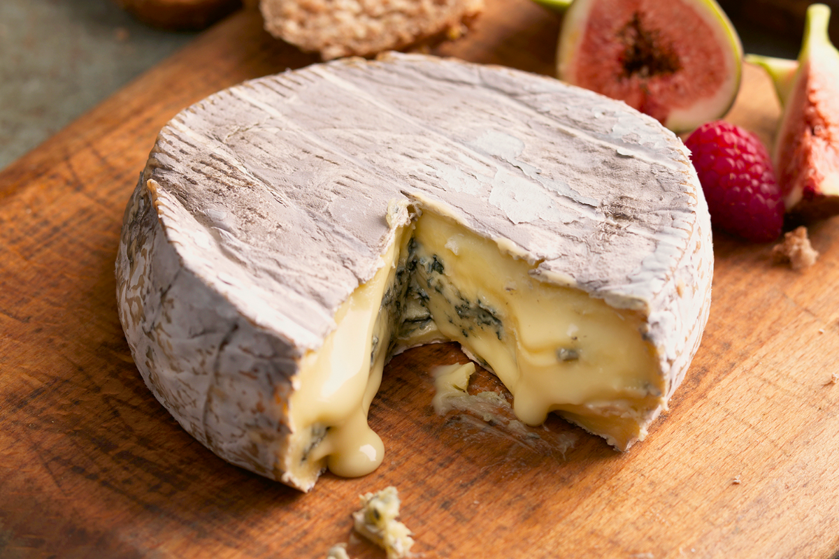 A big slab of blue cheese, oozing out onto a wooden board