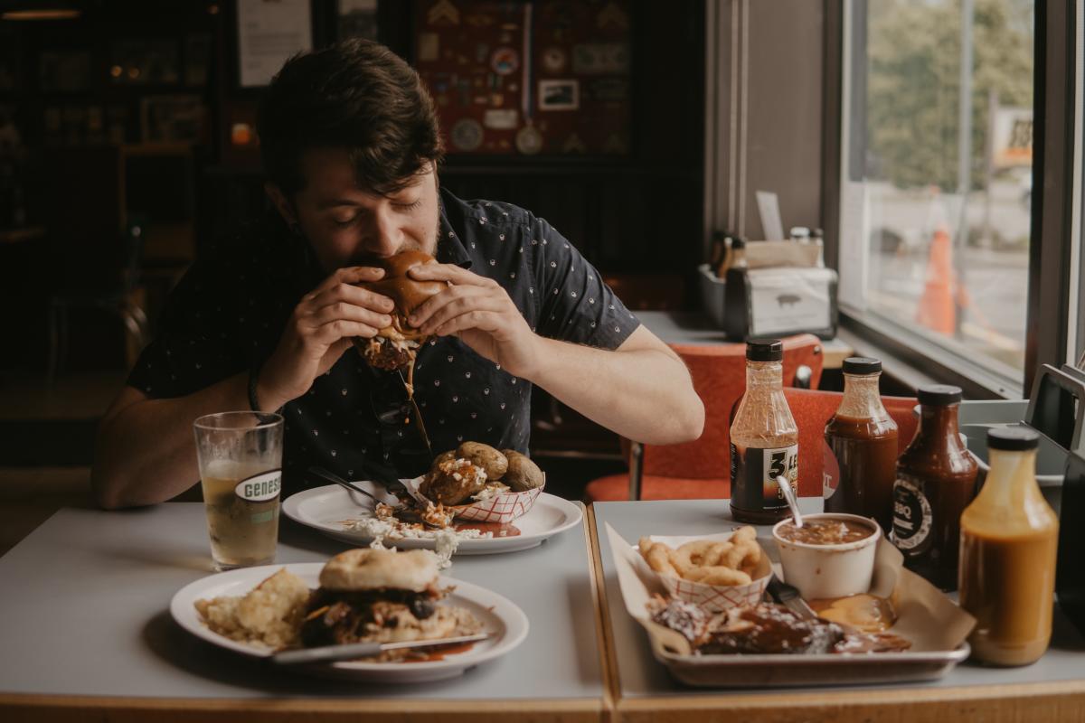 Man Eating at 3 Legged Pig