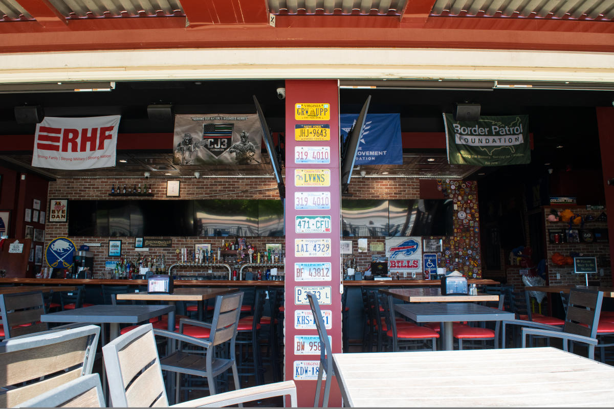Interior bar area at Anchor Bar in Leesburg with license plates, sports flags and full bar visible from outdoor patio