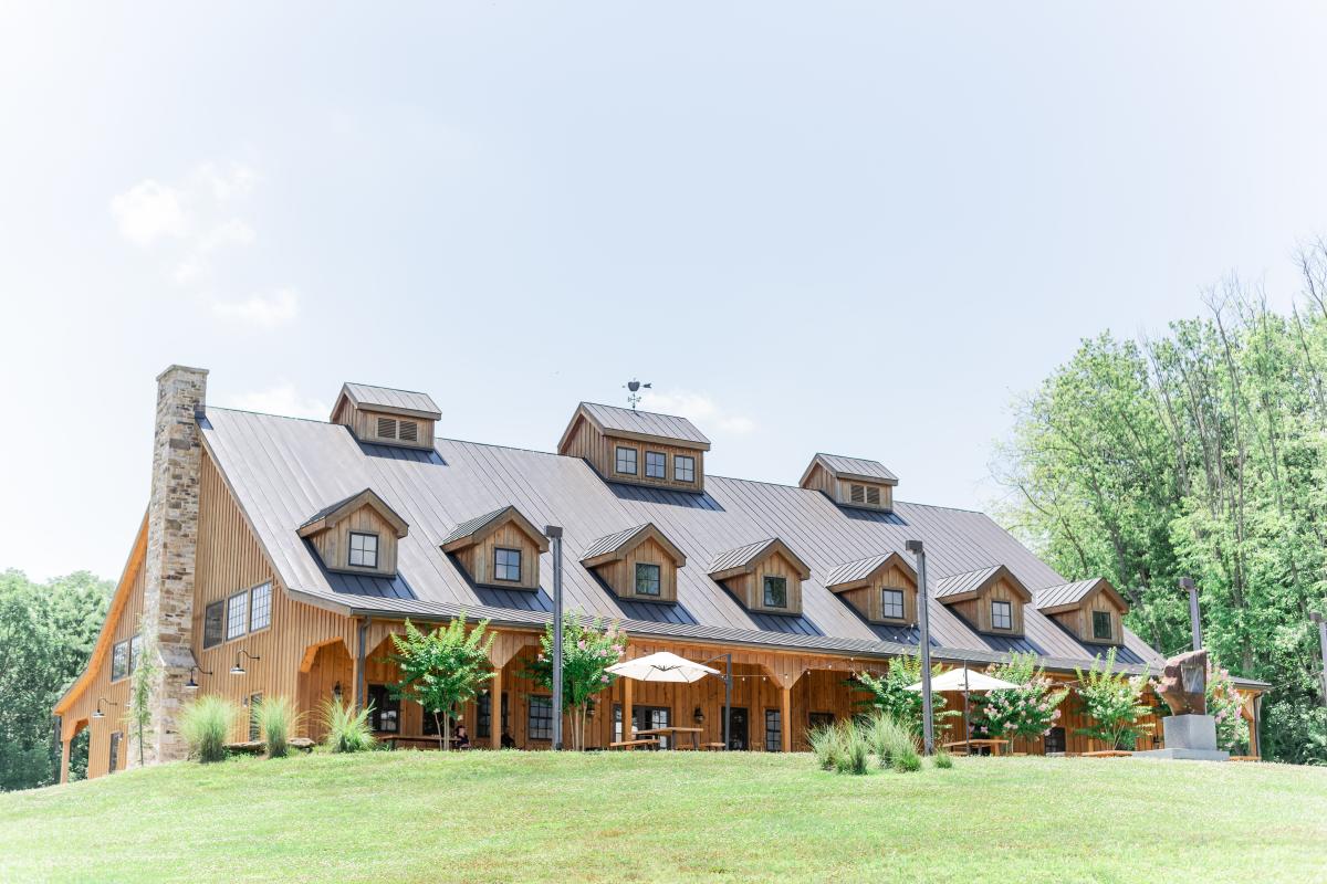 Restored wood barn exterior with covered porch and outdoor seating at Mt Defiance Cidery and Distillery in Middleburg, Loudoun