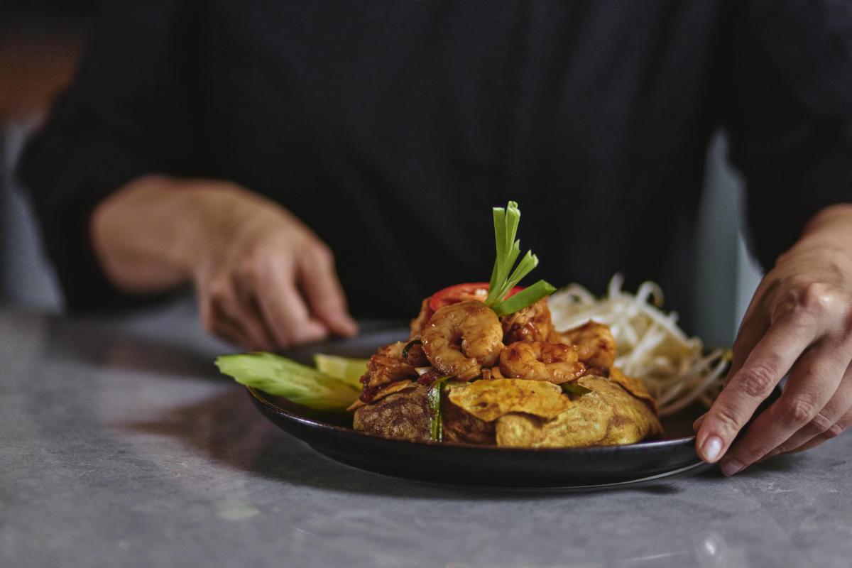 A server places a plated shrimp dish garnished with scallions and tomato at a restaurant in Loudoun County, Virginia