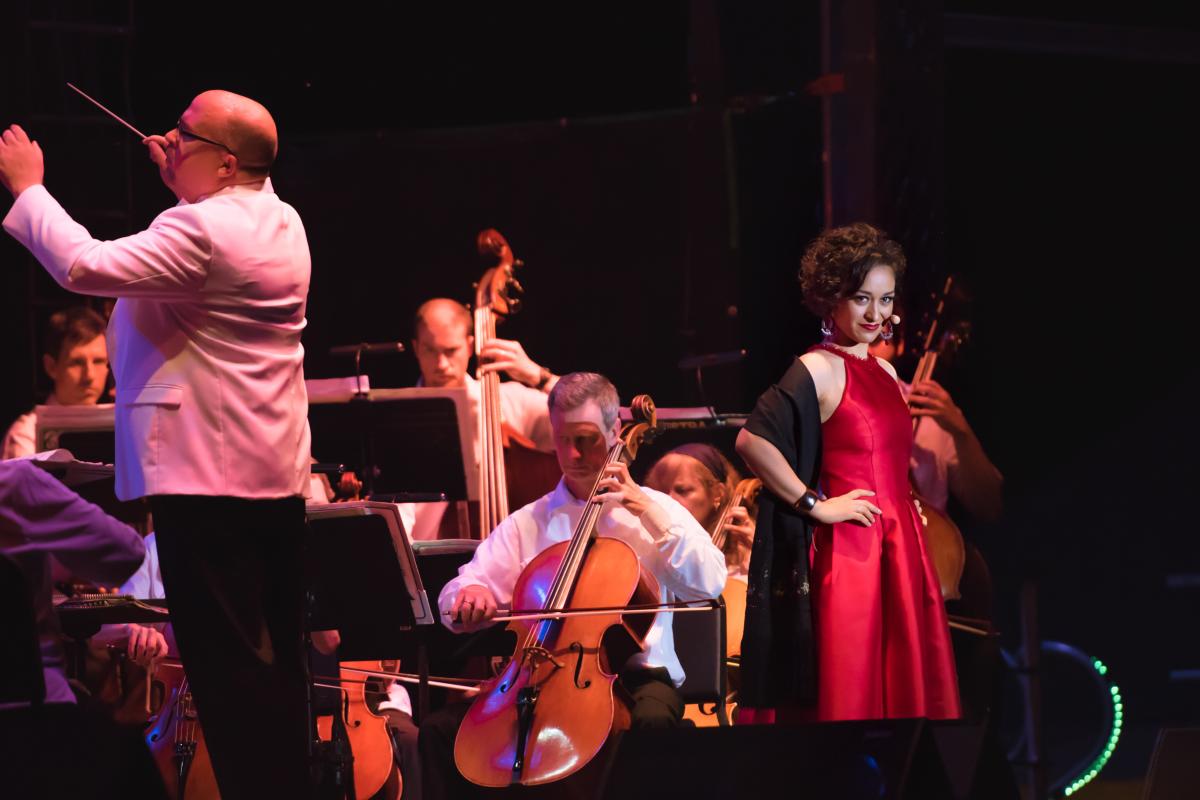 A woman performs opera on stage with an orchestra