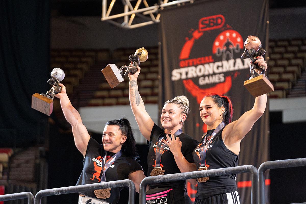 Three Strongman Games competitors hold tropies at Alliant Energy Center in Madison, WI