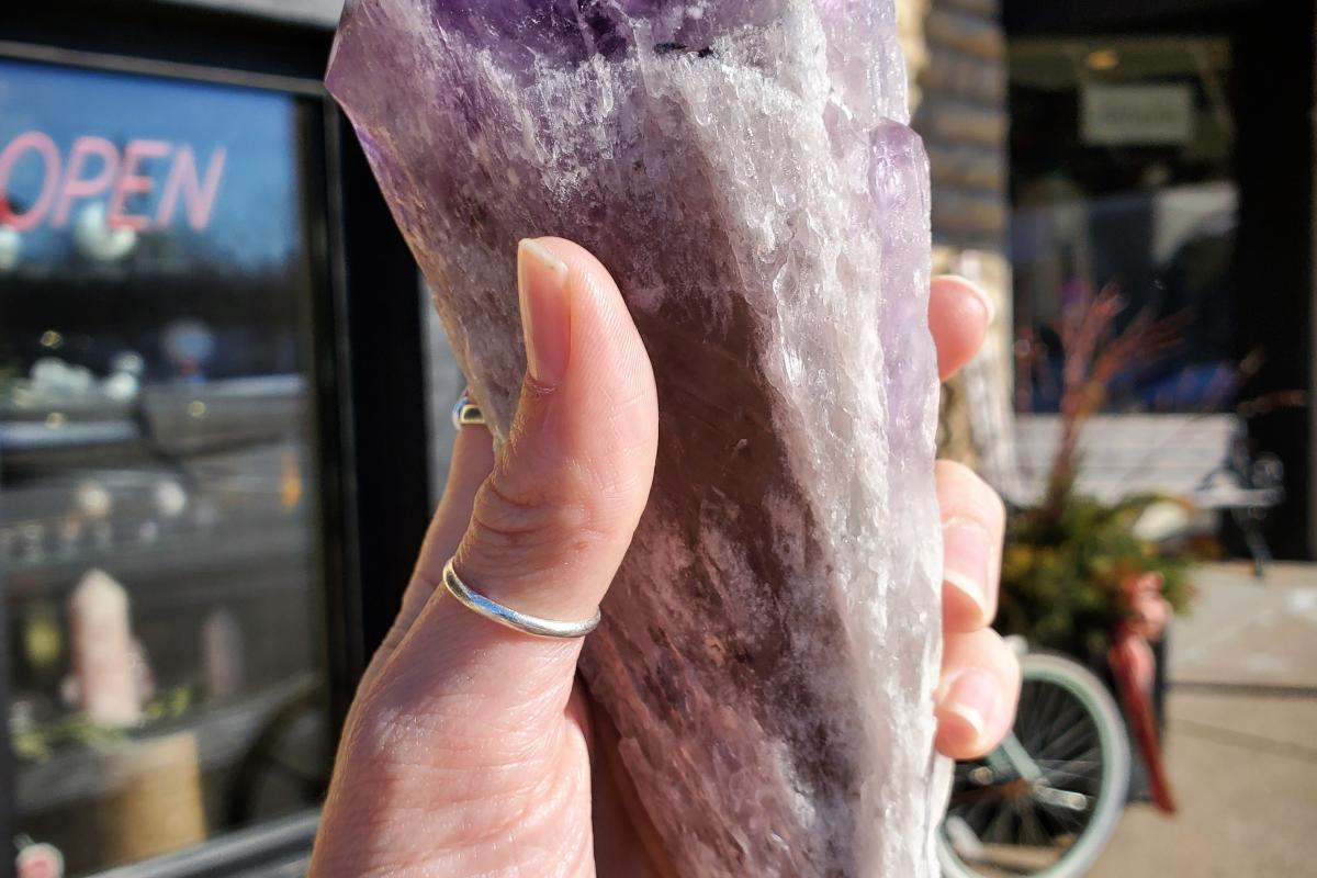 A woman holds a rose colored gem