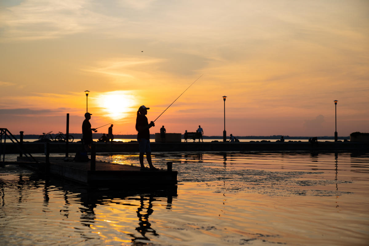 Individual fish off of a pier at the sun sets