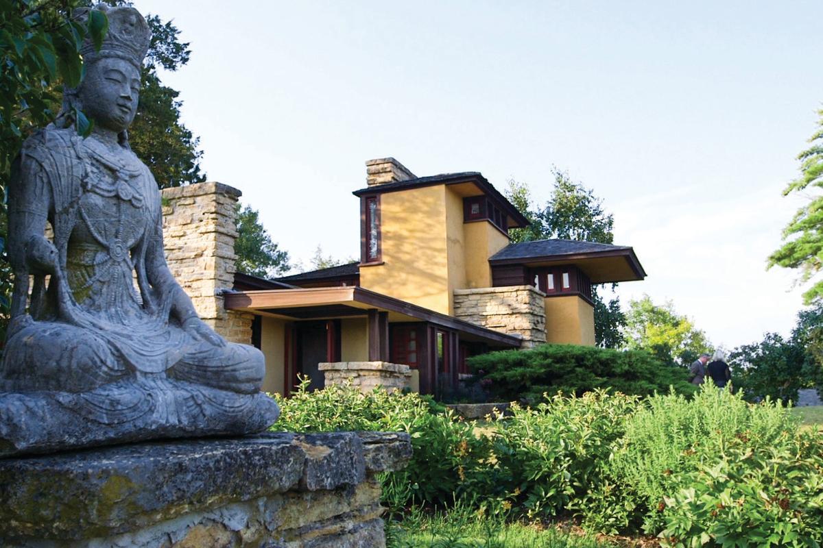 A statute sits outside of a Frank Lloyd Wright-designed building