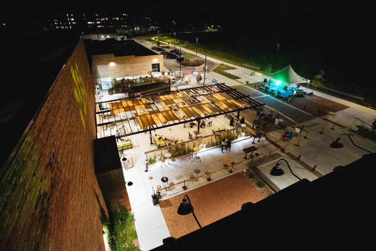 An overhead view of the Garver Feed Mill patio at night, lit up with lights and lots of tables and a stage with a band