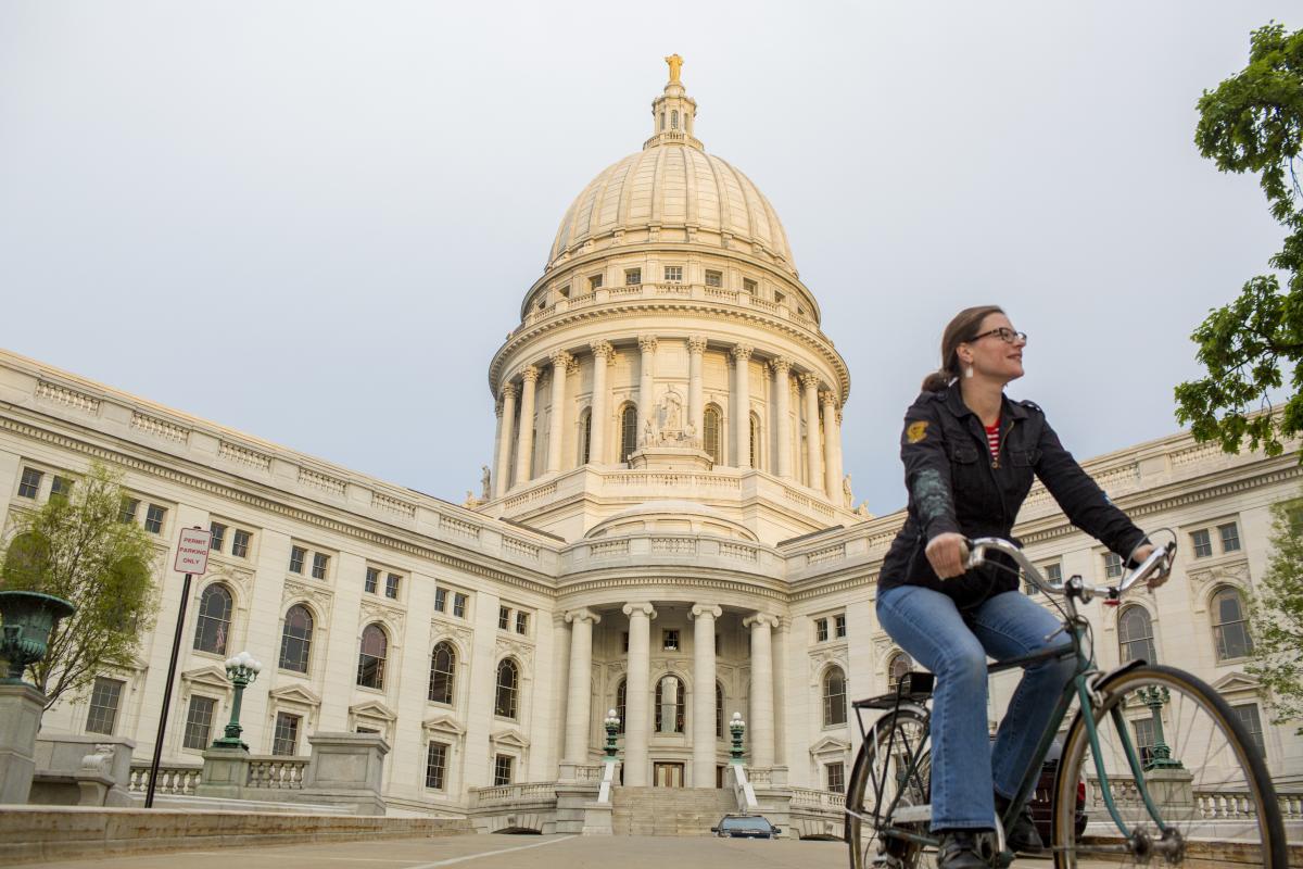 A woman rides her bike in front of the State capitol