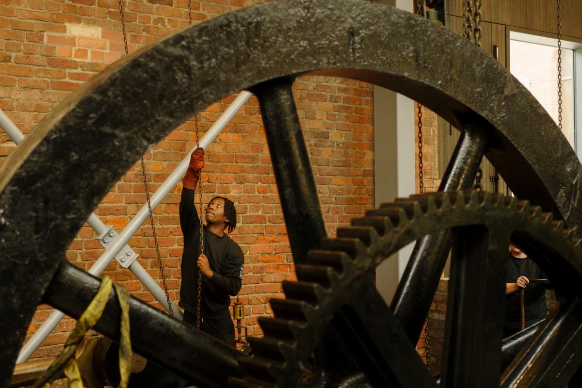 Person working a large wheel in the Power Hall at the Science and Industry Museum