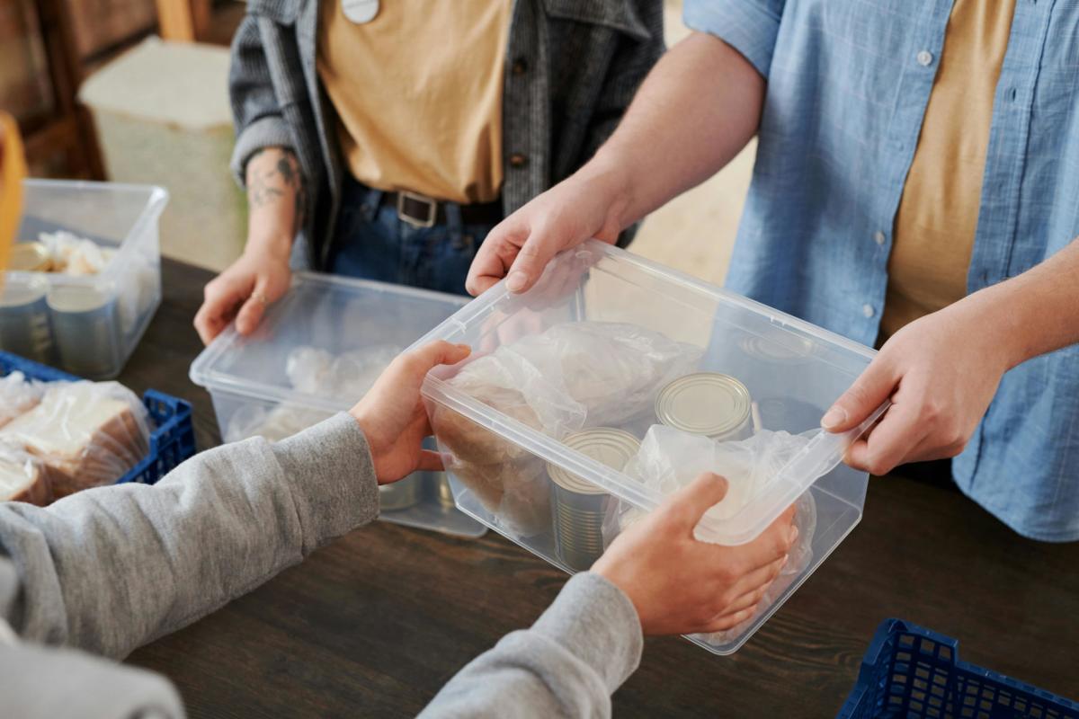 Person handing clear plastic box with food items
