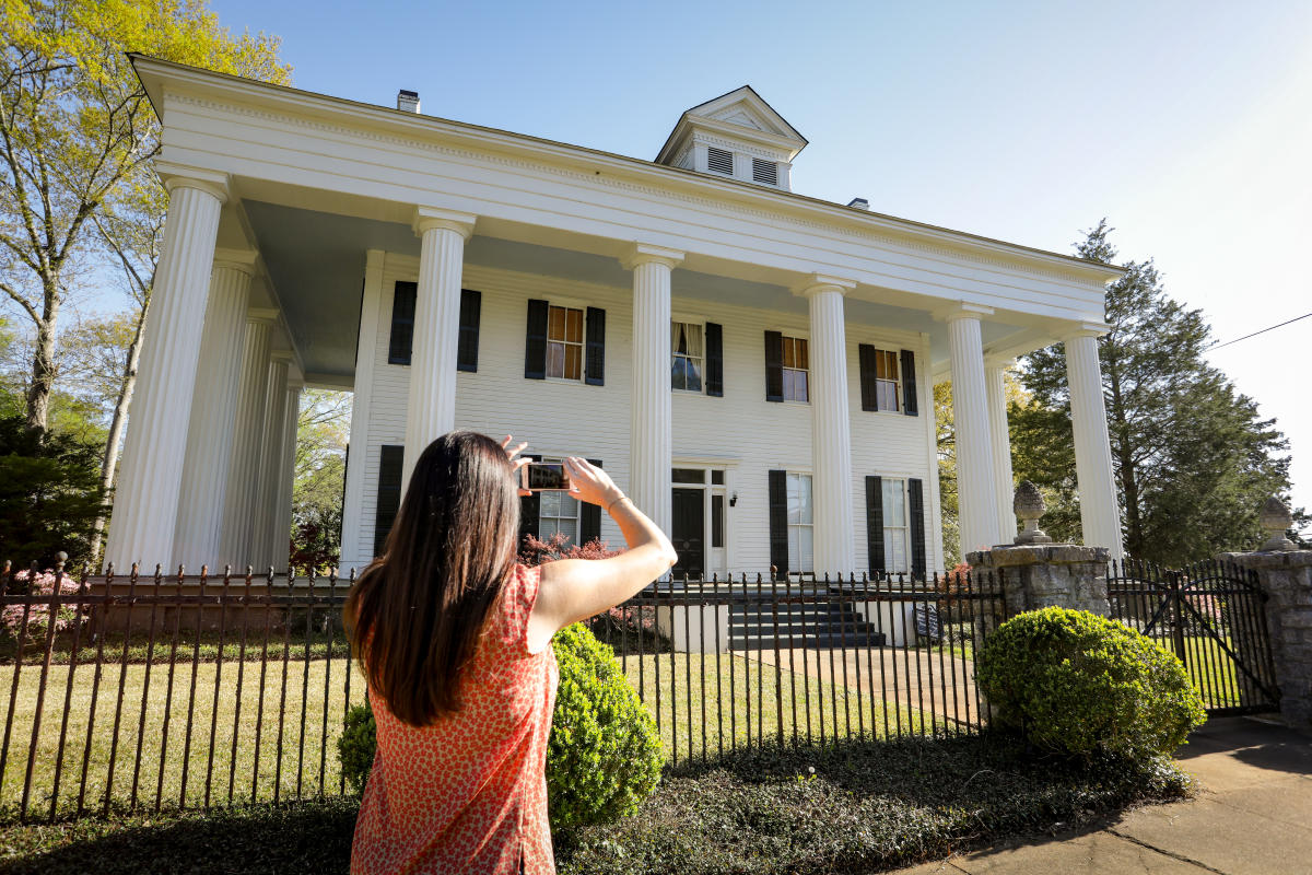 Woman taking picture of historic home in Milledgeville