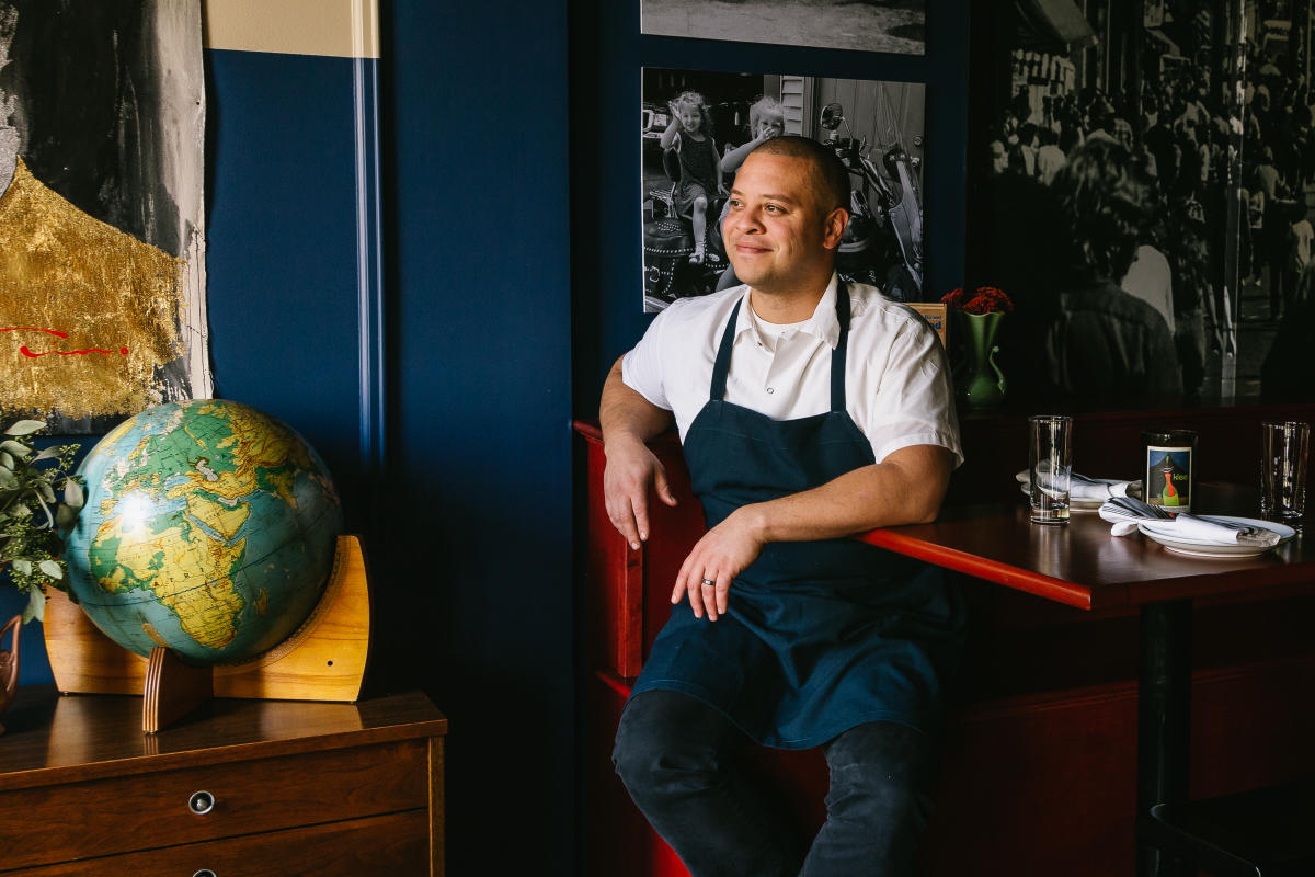a chef sitting on a chair at a dining table in a restaurant