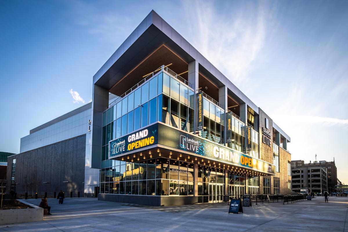 Modern concert venue with a glass facade and large marquee reading “Grand Opening” outside Landmark Credit Union Live in Milwaukee, photographed at sunset with people walking nearby.