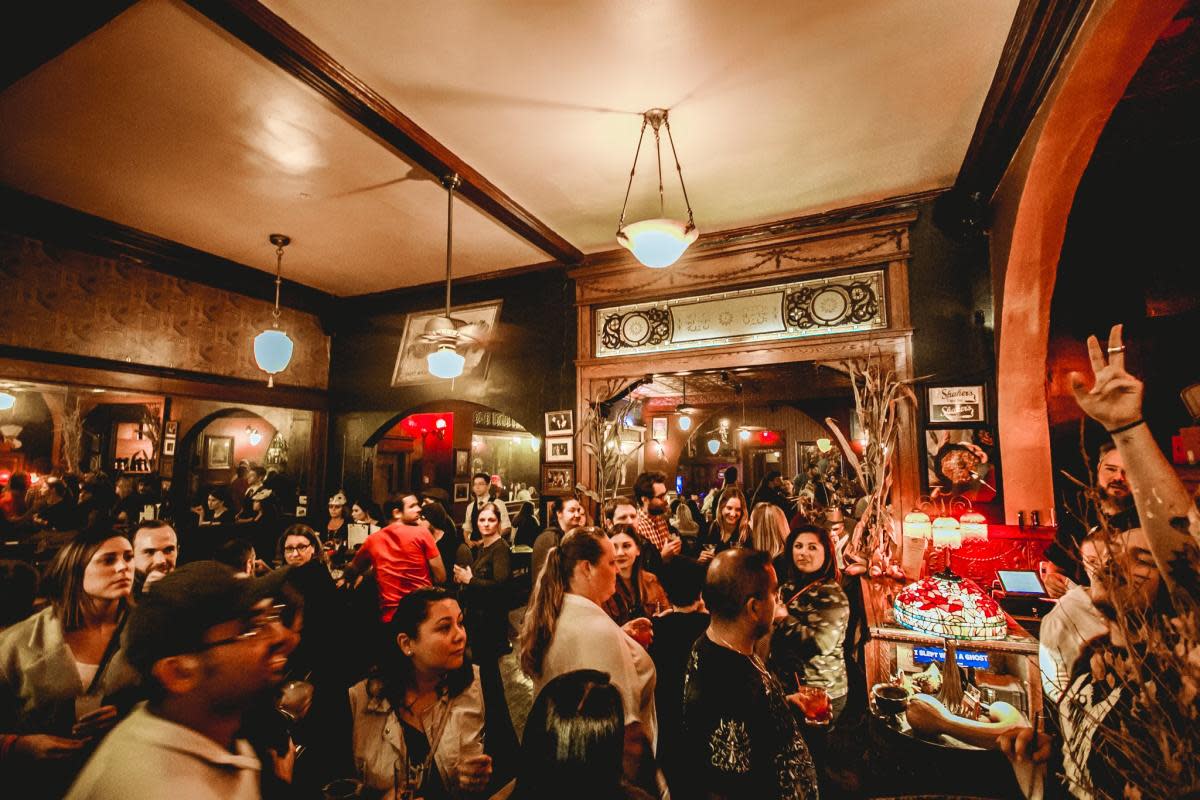 A lively crowd inside Shaker’s Cigar Bar in Milwaukee, with people socializing under warm lighting and vintage decor.