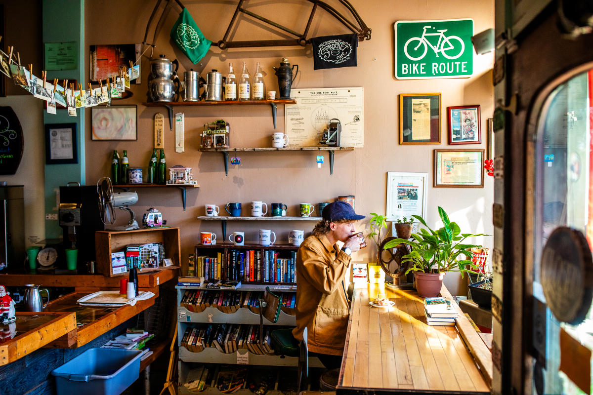 side view of a person sitting at a window drinking a cup of coffee at Sprocket Cafe