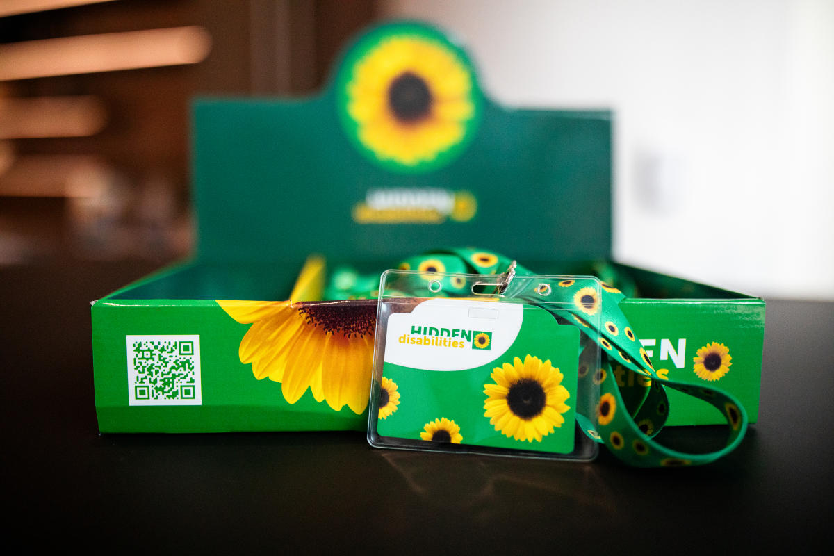 a "Hidden Disabilities" ID card and lanyard are displayed in front of a green sunflower-themed box.
