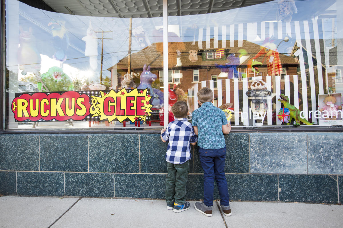 Two children peer in the window of a toy shop