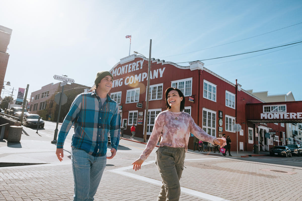 Smiling man and woman walk along Monterey County's Cannery Row.
