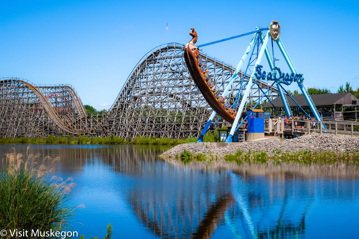 wooden rollercoaster and Seadragon can be seen across blue pond at Michigan's Adventure