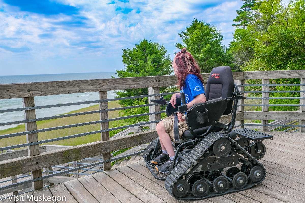 young man in trakchair sits on state park deck overlooking lake michigan