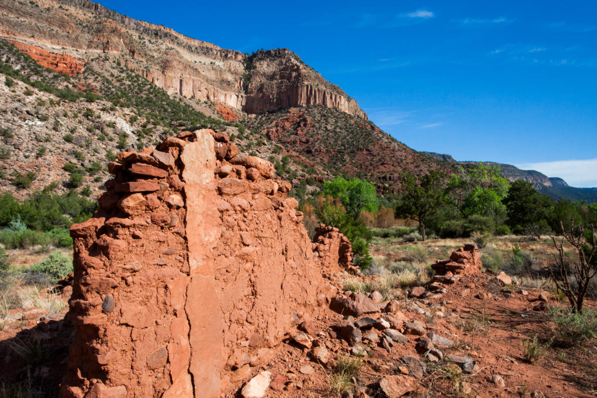 An old brick wall stands in front of large cliffs