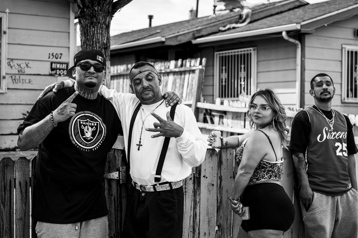 Four people posing together by a wooden fence in a residential neighborhood.